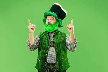 A smiling surprised happy senior man in a leprechaun hat with beard at green studio. He celebrates...