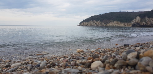 fragment of stony beach with moveable sea wave closeup