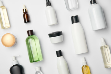 Top view of various cosmetic bottles and containers on white background - obrazy, fototapety, plakaty