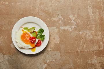 top view of scrambled egg with cherry tomato and avocado in plate on textured background