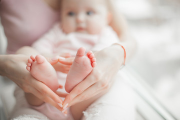 Baby`s feet closeup picture. Mother`s hands holding child`s foot. Little girl`s fingers at front. Background of parenthood.