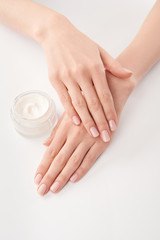 Partial view of woman applying cosmetic cream on white background