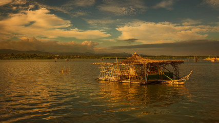 Floating cottage in a bay of water sea wooden bamboo building in evening dusk tranquil scene 