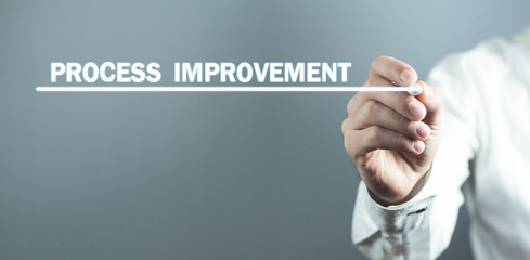 Man with pen write Process Improvement text in screen.