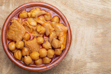 Chickpeas with tripe in clay pot. Aerial (top) view. On wooden background.