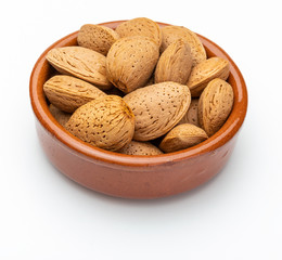 Almonds with shell in clay bowl (Collection of various nuts). Isolated on white background.