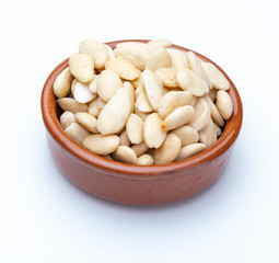 Peeled almonds in clay bowl (Collection of various dried fruits). Isolated on white background.