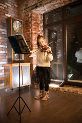 A little girl playing violin by notes