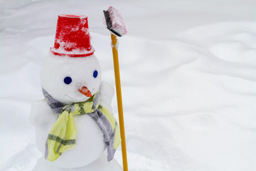 Snowman in red hat and scarf made by children. Closeup, selective focus