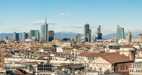 Fototapeta premium Milan skyline. Large panoramic view of Milano city, Italy. The mountain range of the Lombardy Alps in the background. Italian landscape.