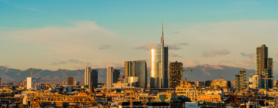 Aerial view of Milan skyline at sunset with alps mountains in the background. © Arcansél