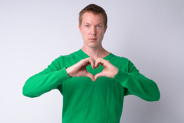 Portrait of young handsome man with hand heart gesture
