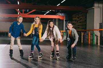 Adorable smiling children preparing to start moving on roller skates