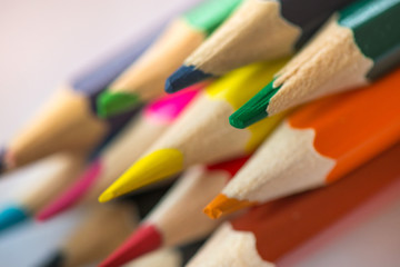 Fototapeta premium Pile of sharp coloured drawing pencils on table. Rainbow colors red, yellow, blue, green, purple. Concept of art, crafts and kids having fun