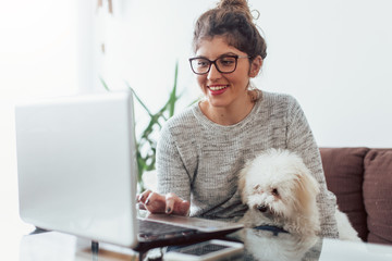 Woman working at home and hugging her puppy