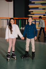 Fototapeta premium Two beautiful smiling children in roller skates standing with holding hands