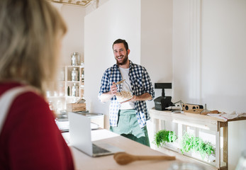 Young shop assistant serving a woman in a zero waste shop.
