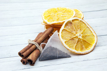 Slices of orange with cinnamon and tea bag on a light wooden background, enjoying the spices