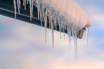 Snow covered roof with row of icicles against sky - obrazy, fototapety, plakaty