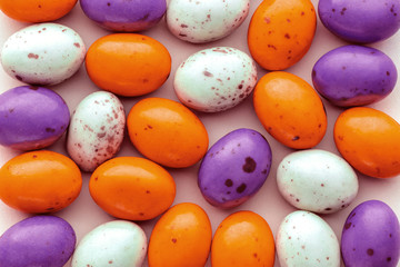 Halloween candy chocolate eggs on a pastel pink background, creative flat lay halloween concept,...