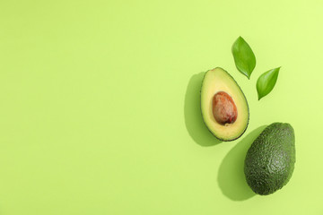 Ripe sliced avocado with green leaves, top view - obrazy, fototapety, plakaty