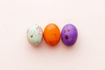 Halloween candy chocolate eggs on a pastel pink background, creative flat lay halloween concept, top view