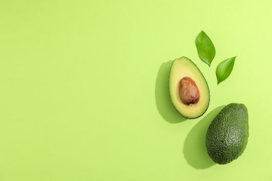 Ripe sliced avocado with green leaves, top view