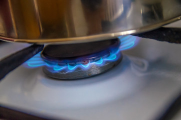 Close-up of a blue flame of a burning gas of a gas stove with a pan - gas burners