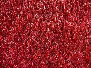 beautiful artificial fur rough texture red color, charming colorful texture glowing background for party decoration board, shiny red color of artificial grass mat, close up red carpet