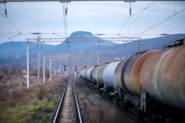 Fototapeta na wymiar Eastern European railroad across Transilvania. Mountain landscape in the background. Scary, dangerous scene in winter with naked trees and polluted nature 