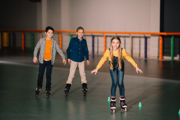 Fototapeta premium Smiling kids in roller skates training on rink
