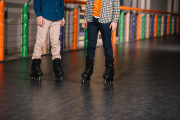 Partial view of boys in black roller skates posing on rink