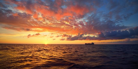 Distant merchant ship sailing in an open Baltic sea on sunset