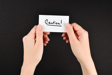 Caution text on a card in woman  on a black background.