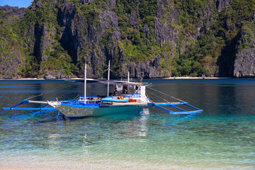 Fototapeta na wymiar Philippine traditional boat in sea water of tropical lagoon. Palawan island hopping tour. Tourist cruise