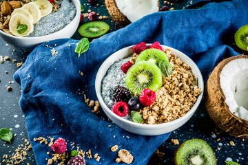 Homemade granola with chia seeds yogurt pudding, fresh fruit and berries, on dark blue concrete background copy space