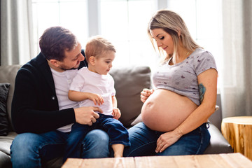 A Beautiful pregnant mother and father with her children at the living room