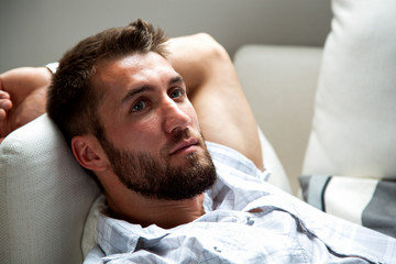 Fototapeta na wymiar Attraktiver junger bärtiger Mann entspannt sich auf der Couch