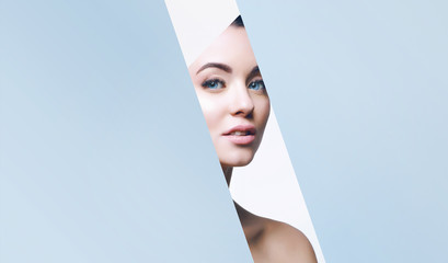 Portrait of young beautiful woman with healthy glow perfect smooth skin look into the hole of...