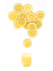 glass with fresh lemon juice is standing under many lemon slices on white background