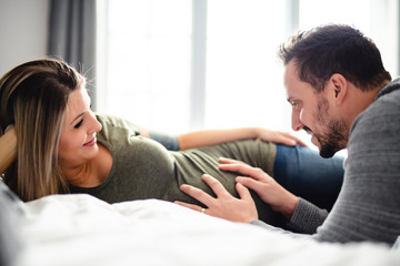 Obraz premium The parents in bed expecting a little baby, Romantic moments for pregnant couple