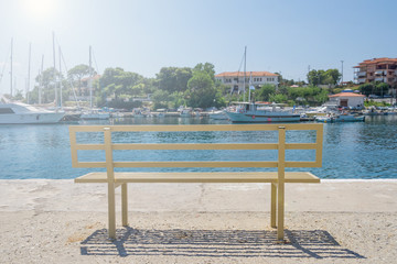 Wooden bench near blue sea water for rest after a walk