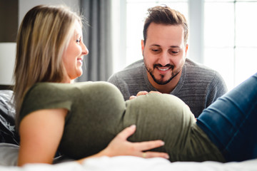 Fototapeta premium The parents in bed expecting a little baby, Romantic moments for pregnant couple