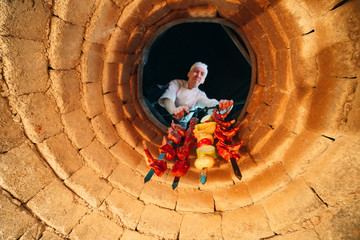 Cooking Kebab in a stone oven. The cook puts the meat in a hot Tandoor oven.