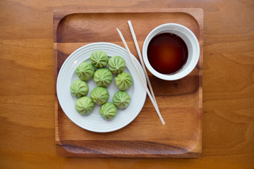 a plate of multiple Dim Sum dumplings and a bowl of soy sauce with chopsticks