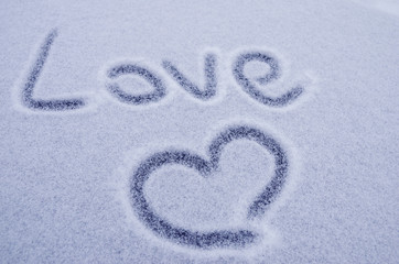 Writing text LOVE on the snow, painted heart on snow. Tinted photo