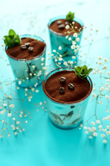 Classic tiramisu in glass on blue background. Italian dessert. Selective focus.