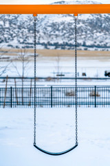 Swing on a playground against a snowy landscape