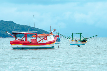 Naklejka na ściany i meble Fishing boats anchored on the sea. Boats at Bombinhas, Praia de Zimbros beach.