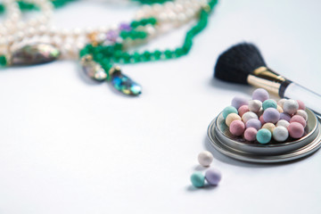 On a white background necklace of pearls, mother of pearl and green stones, powder of colored balls...
